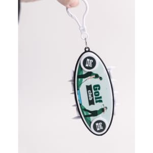 A Golf Tee Set with a black and white oval design, featuring four white golf tees and a logo. It has a keychain attachment.