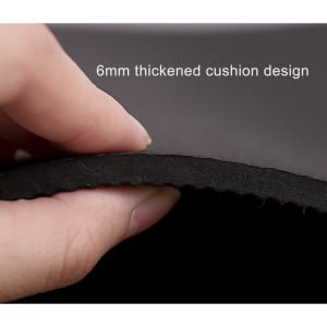 A hand holding the edge of a black yoga mat, highlighting its 6mm thick cushion design.