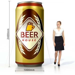An inflatable can design in gold and brown, featuring a logo, beside a person for scale.