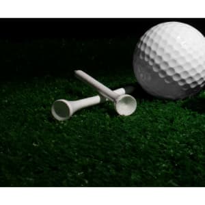 A bamboo golf tee in white, positioned next to a golf ball on green grass.