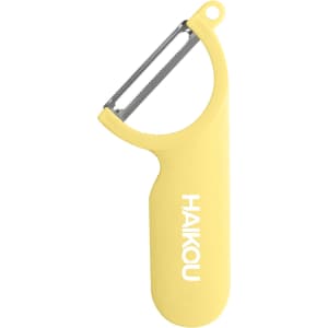 A yellow vegetable peeler with a stainless steel blade and a grip handle, featuring a logo on the side.