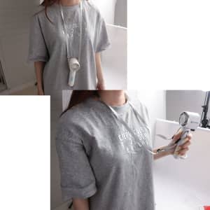 A personal cooling fan in white and blue, hanging from a grey T-shirt, held by a person.
