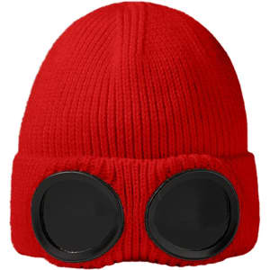 A red beanie featuring black goggles on the front, showcasing a ribbed texture and fold-over cuff.