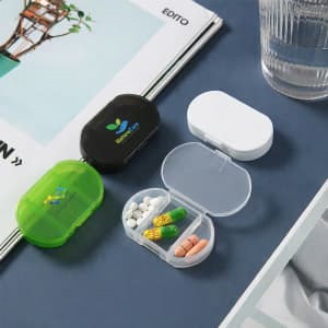 Three pill boxes in green, black, and white, displaying various pills inside a transparent compartment.