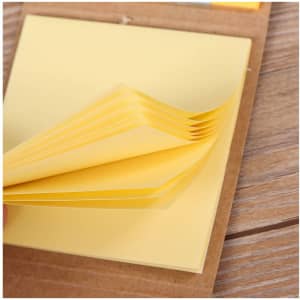 A set of yellow mini sticky notes with a brown holder, displaying stacked notes ready for use.