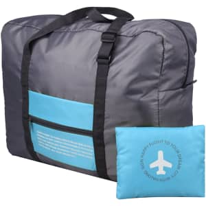 A grey travel compressed bag with a blue pocket and a matching blue pillow. The bag features handles and a logo.