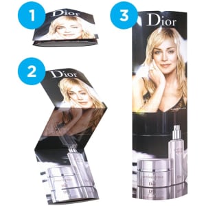 A cardboard display featuring a model and Dior skincare products, predominantly in shades of white and light grey, with a logo.