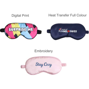 A collection of three satin sleep masks in multi-coloured, navy, and pink designs, each featuring different prints and branding.