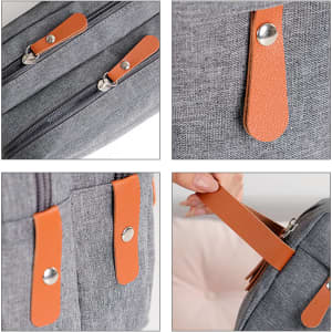 A classic toiletry bag in grey fabric with brown leather accents and zippered compartments. Features sturdy zippers and handles.