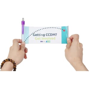 A hands holding a promotional banner with a purple plastic pen attached, featuring a logo and colourful design.