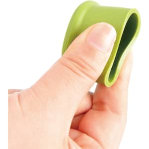 A drink bottle top with a green silicone wine stopper being held by a hand, showcasing its flexible design.