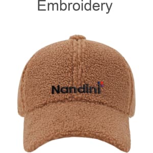A tan lamb fur baseball cap with a curved brim and a logo embroidered on the front.