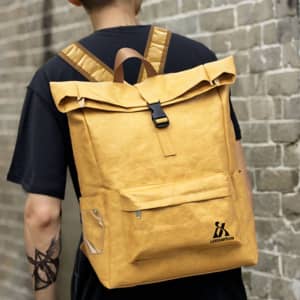 A yellow Tyvek roll top backpack worn on a person's back, featuring a logo and adjustable straps.