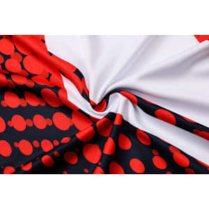 A close-up of a sublimated football jersey featuring a red, white, and black design with circular patterns and a logo.