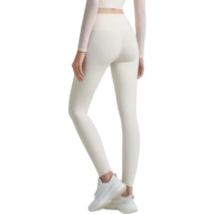High-waisted elastic LYCRA yoga leggings in a light cream colour, featuring a logo on the waistband.