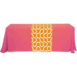 A pink table with a small orange and white patterned table runner in the centre, featuring a swirling design.