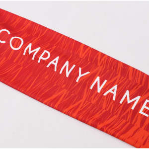 A red sublimated fabric with a textured pattern, featuring a logo or branding prominently displayed.