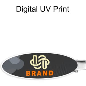 An oval acrylic hair clip featuring a dark design with a logo and vibrant colours.