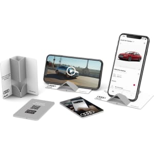 A range of grey and white pop-up phone stands displaying different electronic devices and a QR code card.