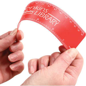 A flexible red ruler is being held between two hands, featuring measurement markings along its length and a logo.