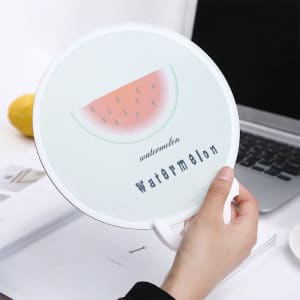 A foldable fan with a watermelon design and handle, featuring a light green background and a logo.