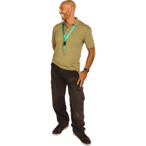 A man wearing a green 100% rPET lanyard and an olive polo shirt, standing in a relaxed pose. The lanyard features a logo.