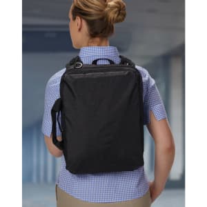 A black utility laptop bag is worn on the back of a person dressed in a checked shirt. The bag has a logo.