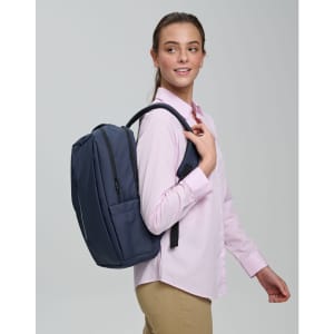 A navy PU backpack is carried on one shoulder by a smiling model wearing a light pink shirt.