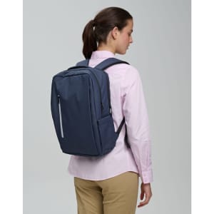 A navy blue backpack with a sleek design is worn by a person facing away, showcasing its minimalist style.