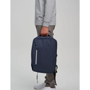 A navy blue PU backpack is being held by a person. The backpack features a zipper and has a logo.