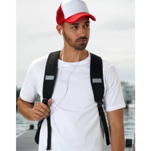 A black backpack worn by a man in a white t-shirt and a red and white cap, with earbuds visible.