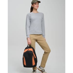 A woman wearing a grey top and khaki pants holds a black and orange Iconic Promo Backpack.