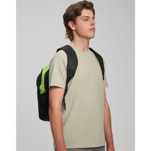 A backpack in black with lime green accents is worn on one shoulder by a young man in a light grey shirt.