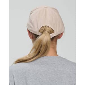 A light beige cap with a five-panel design, featuring an adjustable strap at the back.