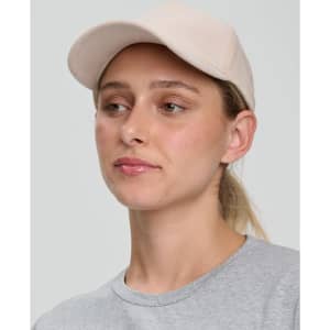 A beige Jacquard Texture 5 Panel Cap worn by a woman, featuring a curved brim and a minimalist design.