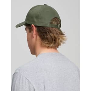 A green cotton twill unstructured cap viewed from the back on a person with long hair, wearing a grey shirt.