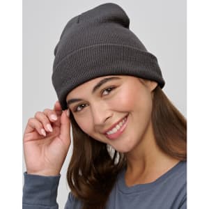 A dark grey beanie made from recycled materials, worn by a smiling woman, featuring a simple ribbed design.