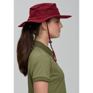 A maroon surf hat with a wide brim, featuring a chin strap and ventilation holes, worn by a person with long hair.