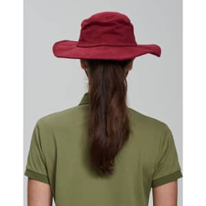 A maroon surf hat viewed from the back, worn by a person with long brown hair, paired with an olive green shirt.