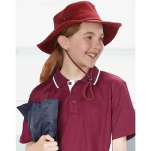 A red bucket hat worn by a smiling girl, paired with a maroon polo shirt and holding a navy blue item.