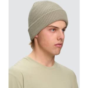 A beige cable knit snug beanie displayed on a model, featuring a ribbed design and a logo.