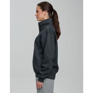 A grey 1/2 zip collar fleecy jumper displayed on a model from the side, featuring a smooth fabric and a logo.