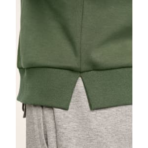 A green crew neck sweater featuring ribbed hem details and a split at the bottom, paired with grey joggers.