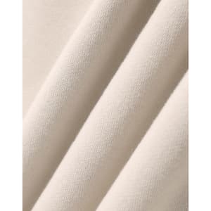 A close-up of soft, beige fabric showcasing the texture of an oversized fleece hoodie. It includes a logo.