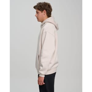 A unisex premium fleece oversized hoodie in light beige, featuring a hood and a front pocket, with a logo visible.