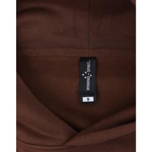 A brown unisex oversized hoodie with a tag displaying size information and a logo.