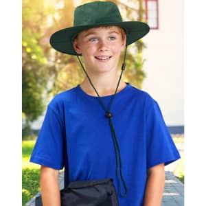 A boy wearing a green slouch hat with a break-away clip, paired with a blue t-shirt, smiles outdoors.