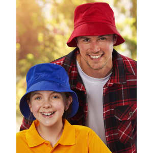 A red bucket hat and a blue bucket hat worn by a man and a girl, both smiling. The background is blurred greenery.