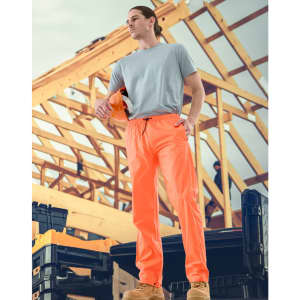 Lightweight nylon waterproof rain pants in bright orange, modelled by a person on a construction site.