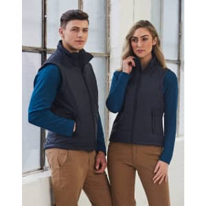 A navy padded vest featuring a zip front and side pockets, modeled by a man and woman in casual attire.